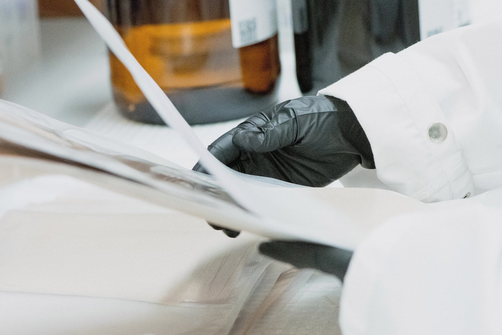 Person in a lab coat working with bottles and a pipette on a lab bench.