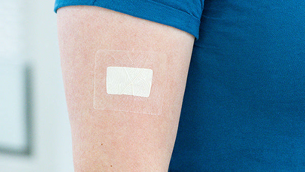 Person wearing a blue shirt with a SkinSync Patch on their arm.